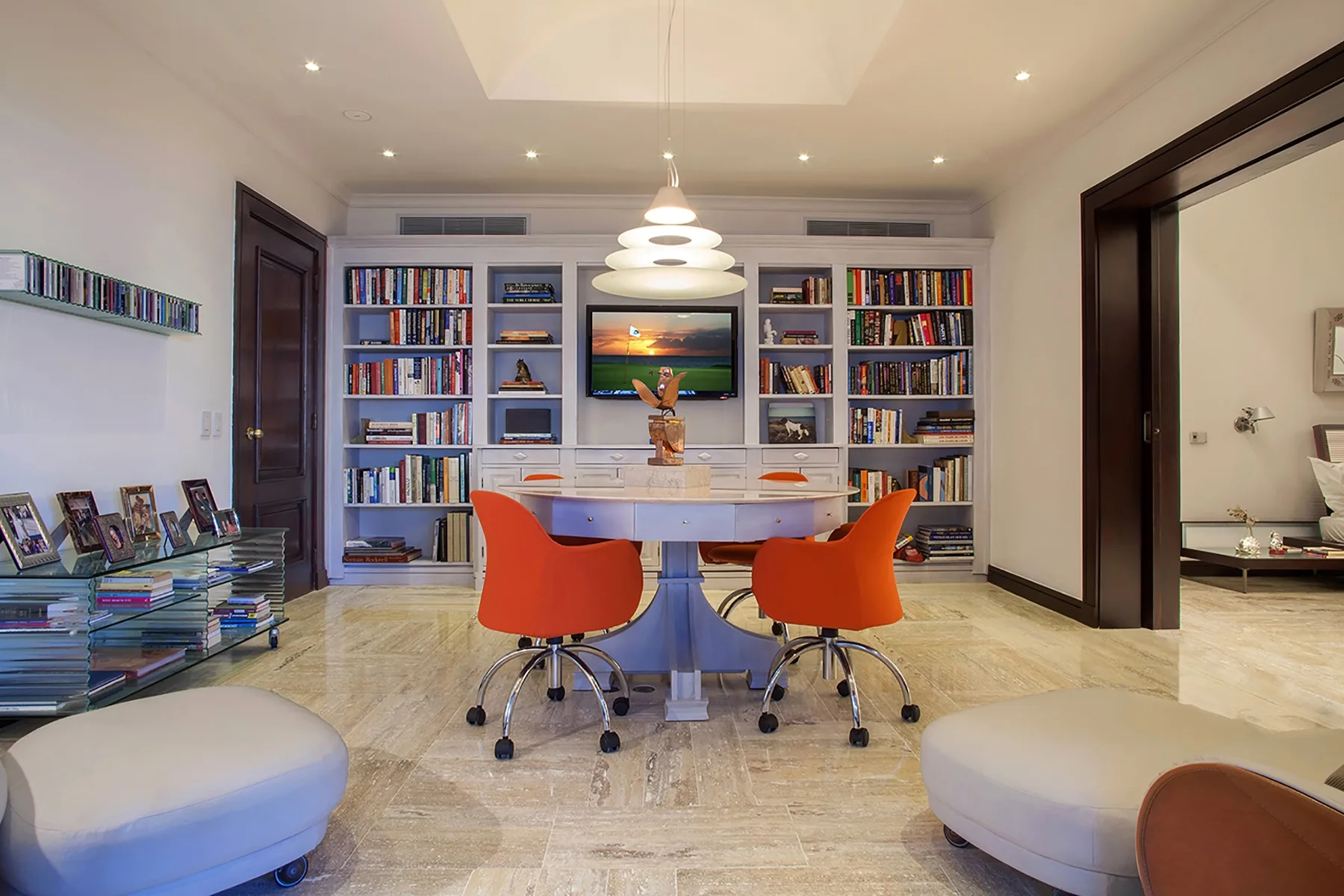 A bright study with built-in bookshelves, a desk, and red seating.