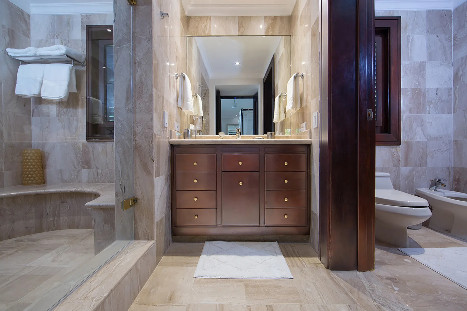 A bathroom with a double-sink vanity, mirror, and separate bathing areas.