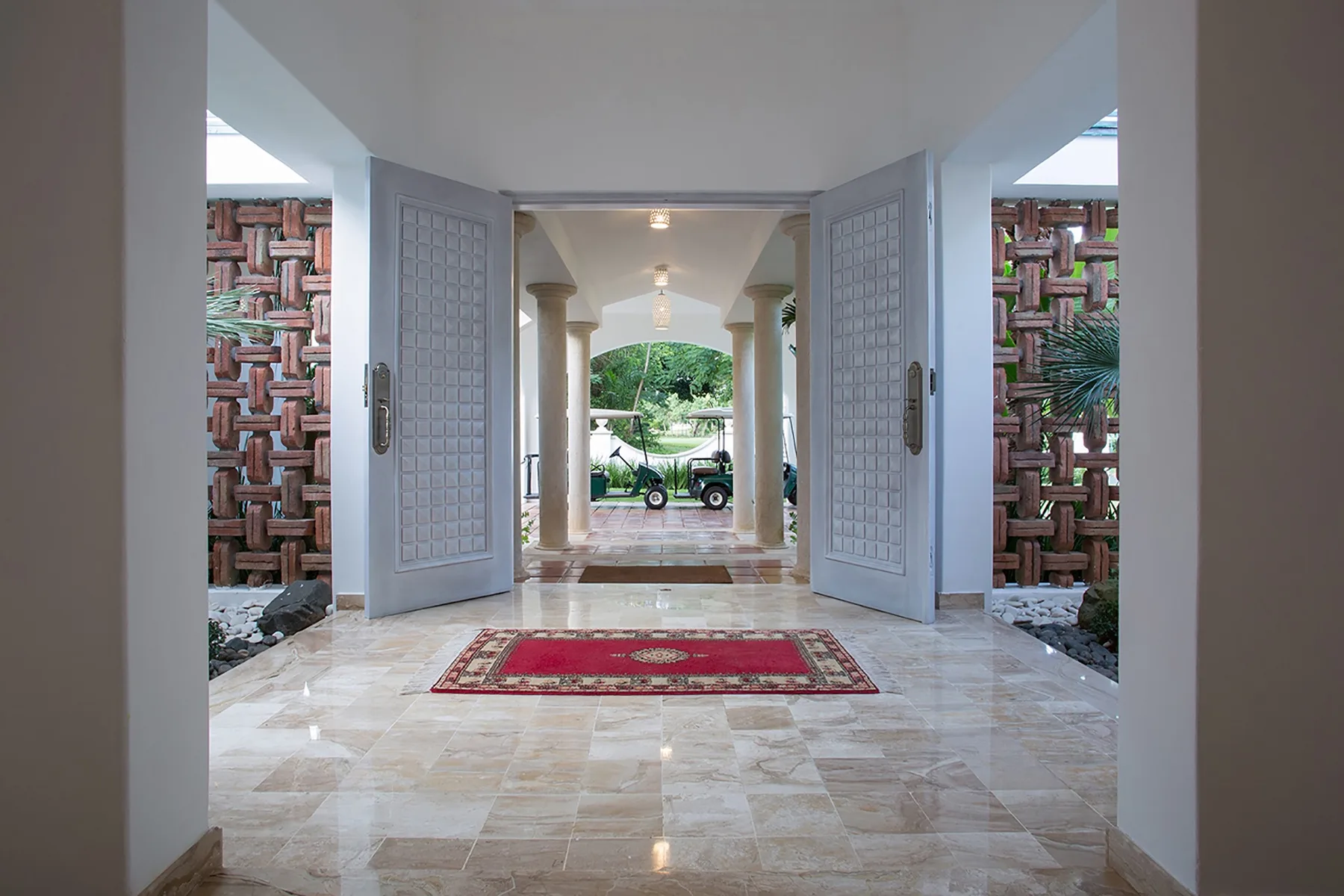 An open entryway with double doors and a red rug on the floor.