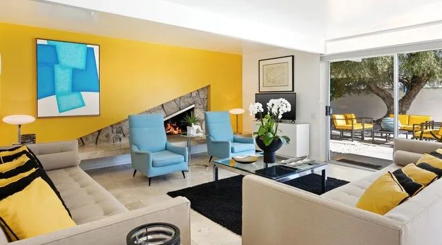 Una sala de estar luminosa con asientos azules y una mesa de centro de vidrio.