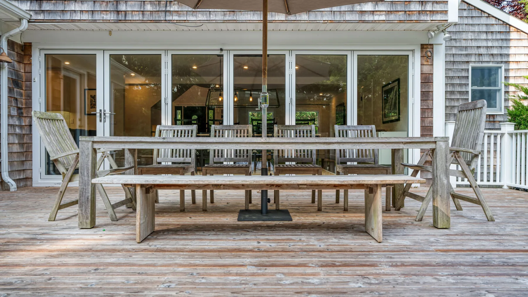 Un comedor al aire libre con una mesa larga de madera y bancos sobre una terraza.
