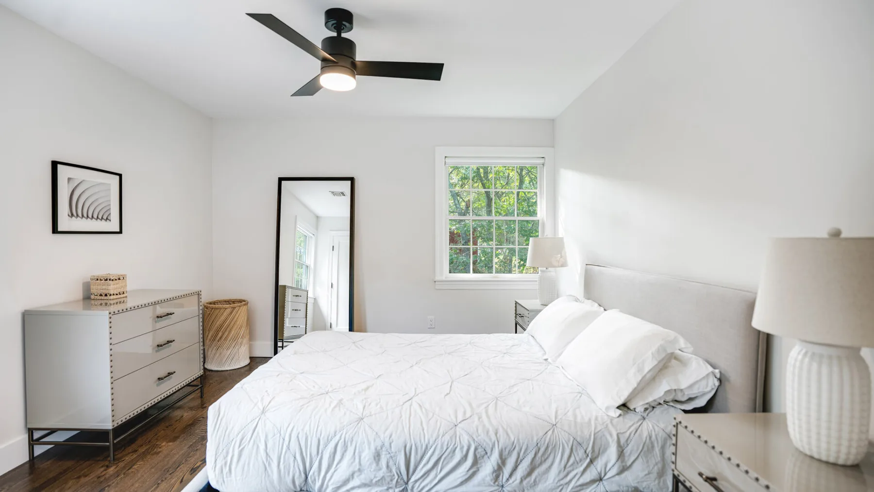 Un dormitorio luminoso con una cama, una cómoda y una ventana.