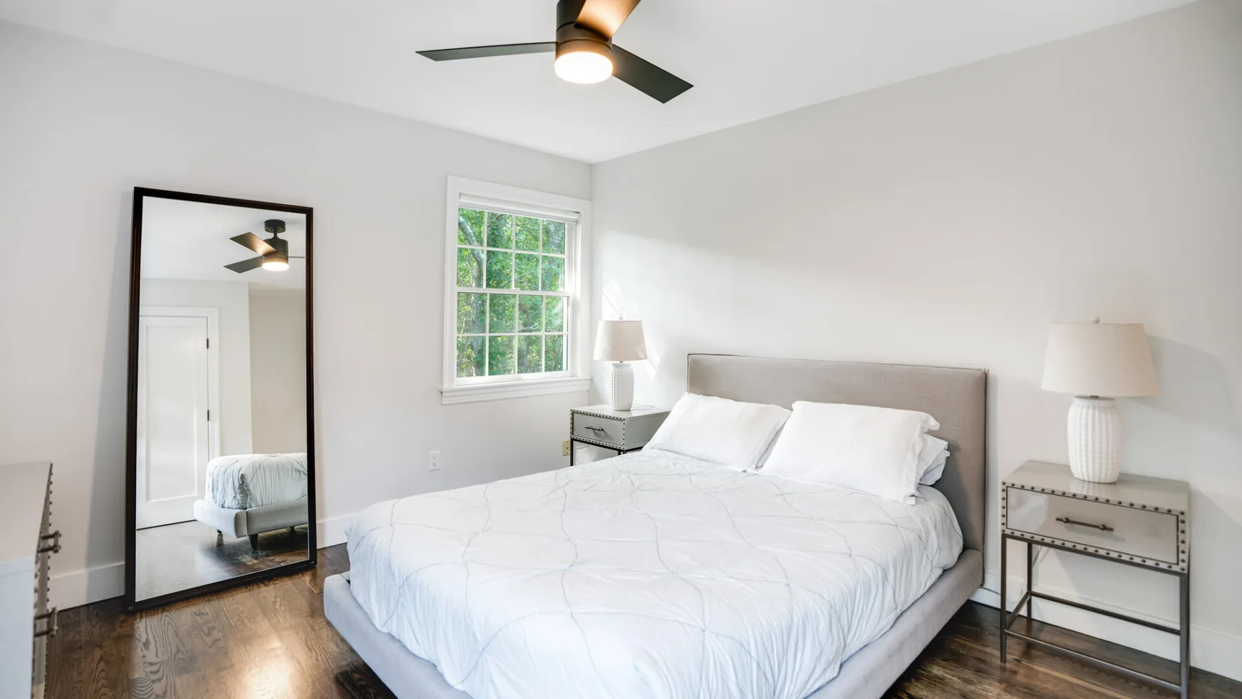 Un dormitorio luminoso con una cama, una ventana y un ventilador de techo.