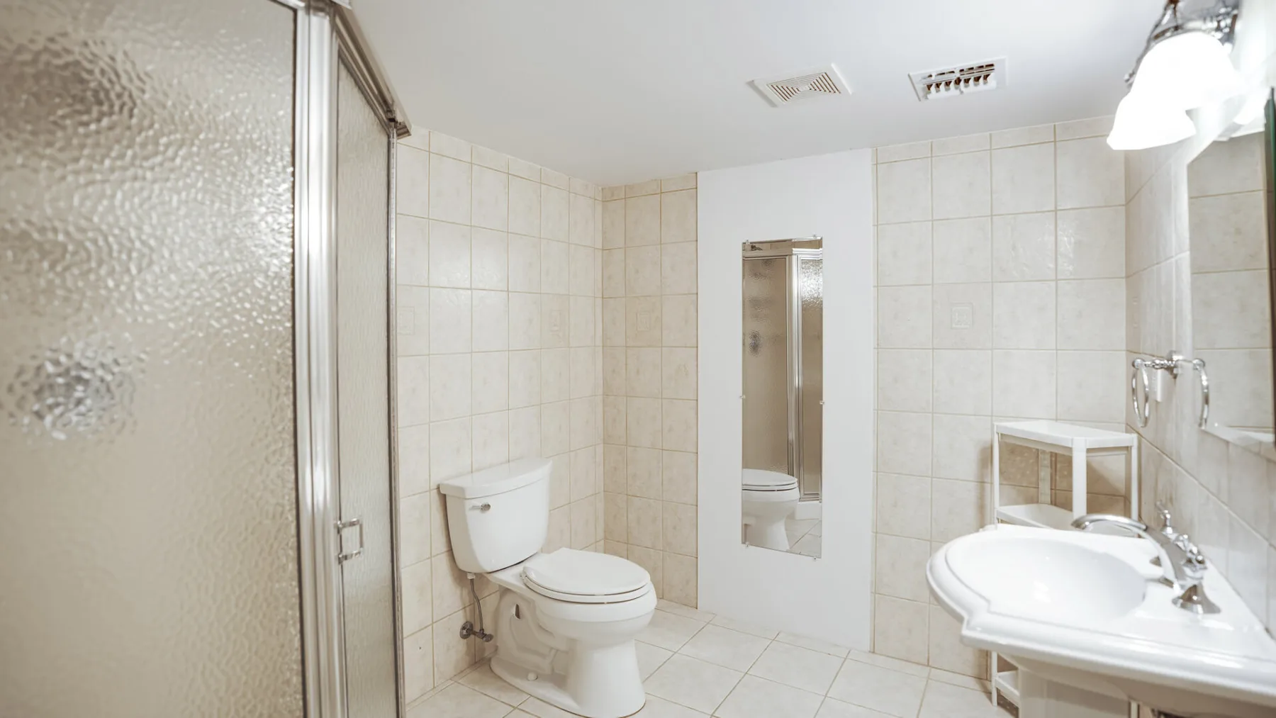 Un baño con azulejos, ducha, inodoro y lavabo.