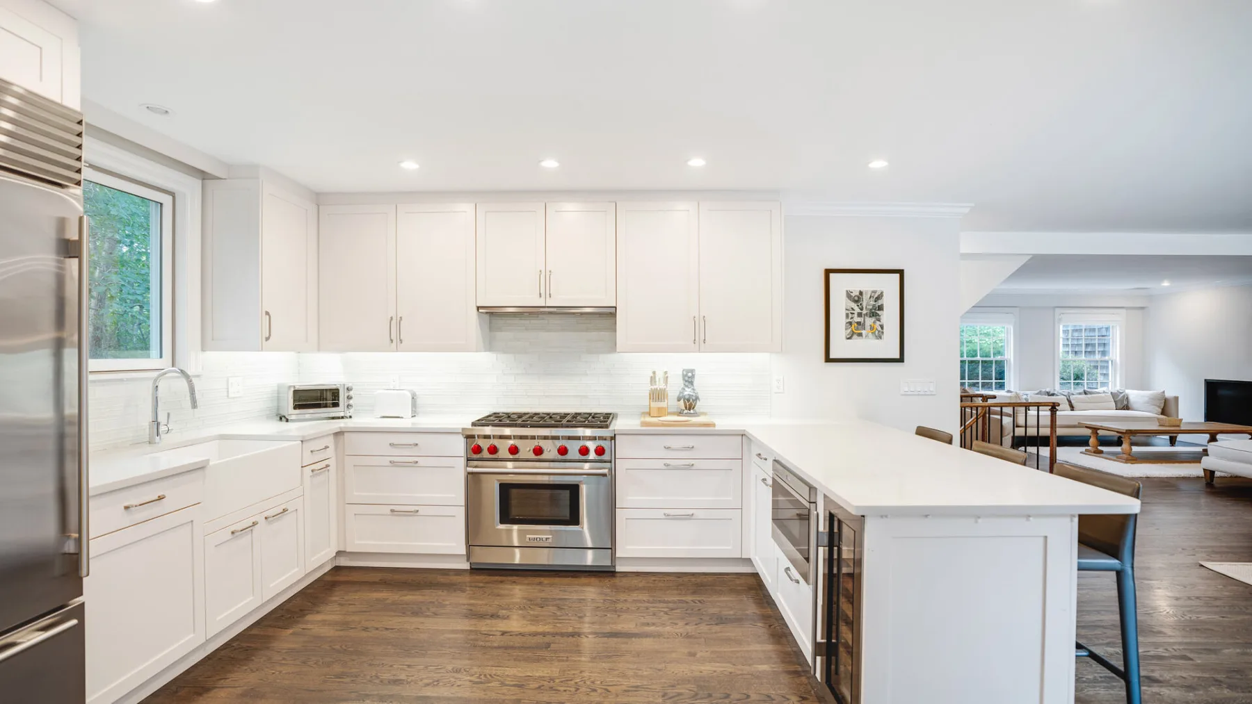 Una cocina blanca y luminosa con una isla central y electrodomésticos de acero inoxidable.
