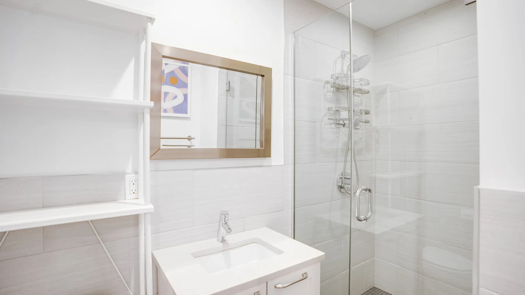 Un baño luminoso con lavabo, espejo y ducha de vidrio.