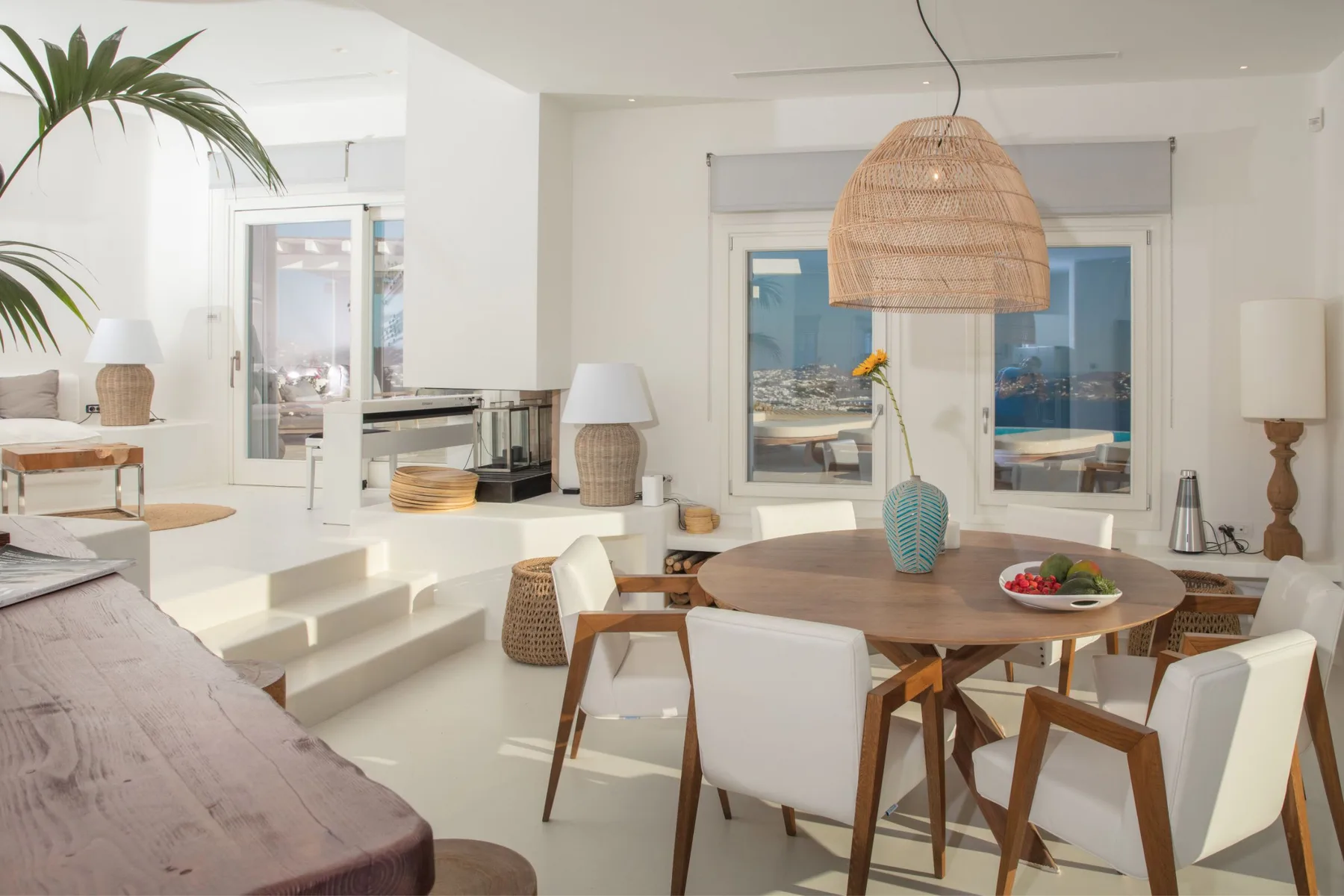 A bright dining area with a wooden table and chairs beside large windows.