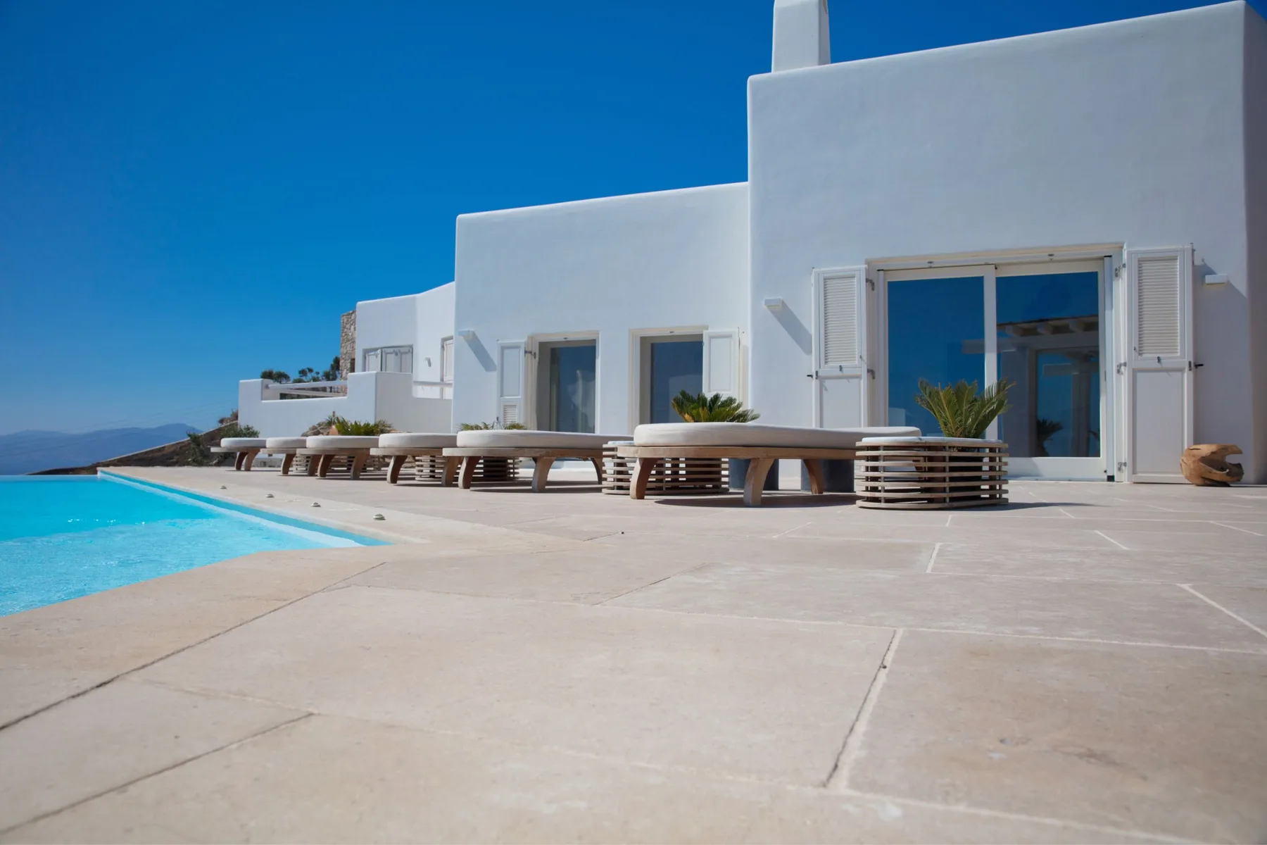 A white building with outdoor seating beside a swimming pool.