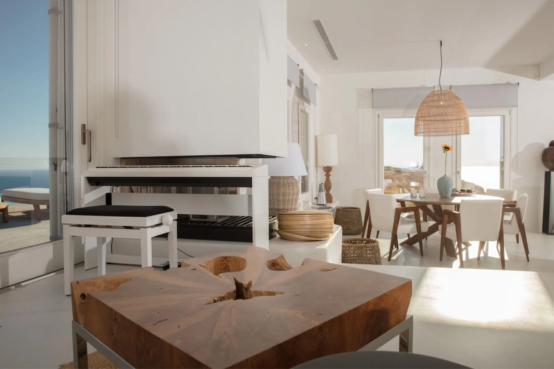 A bright open-plan living and dining area with a wooden coffee table and dining table.