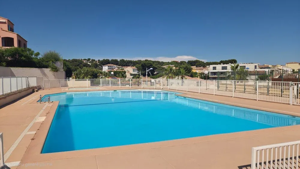 An outdoor swimming pool with a paved deck and surrounding fence.