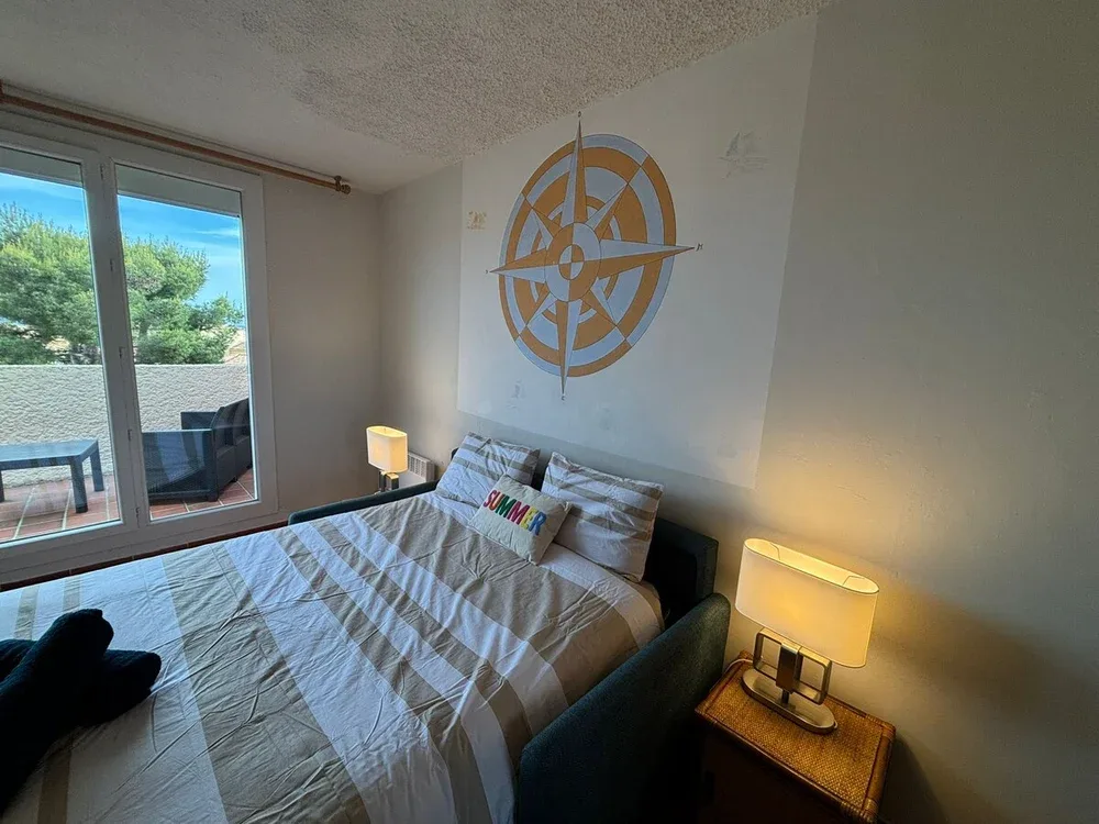 A bedroom with a bed beneath a large compass design on the wall.