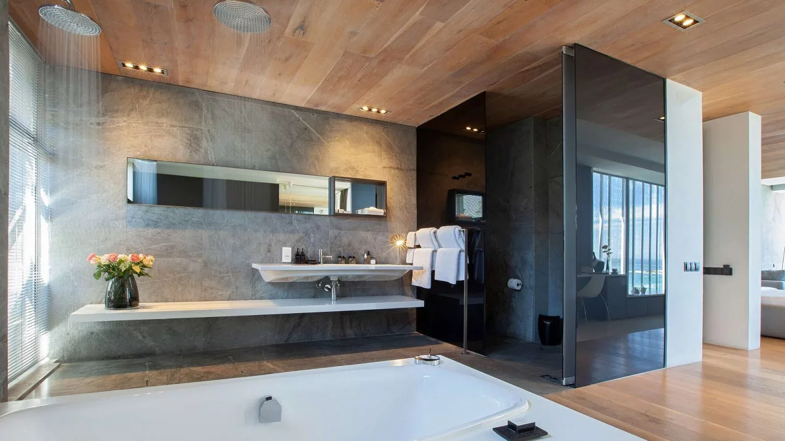 Baño elegante y moderno de la suite Deluxe, con bañera exenta y ducha de lluvia