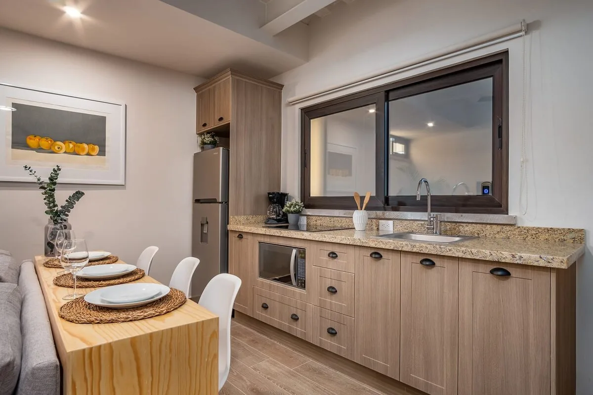 Cocina y comedor modernos con gabinetes de madera, cubiertas de granito y una mesa de madera puesta para comer