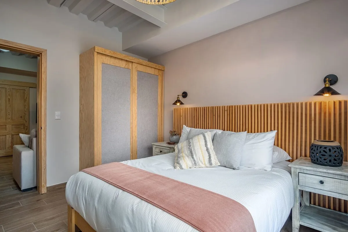 Bedroom with king bed, wooden slatted headboard, and wardrobe closet with fabric panels