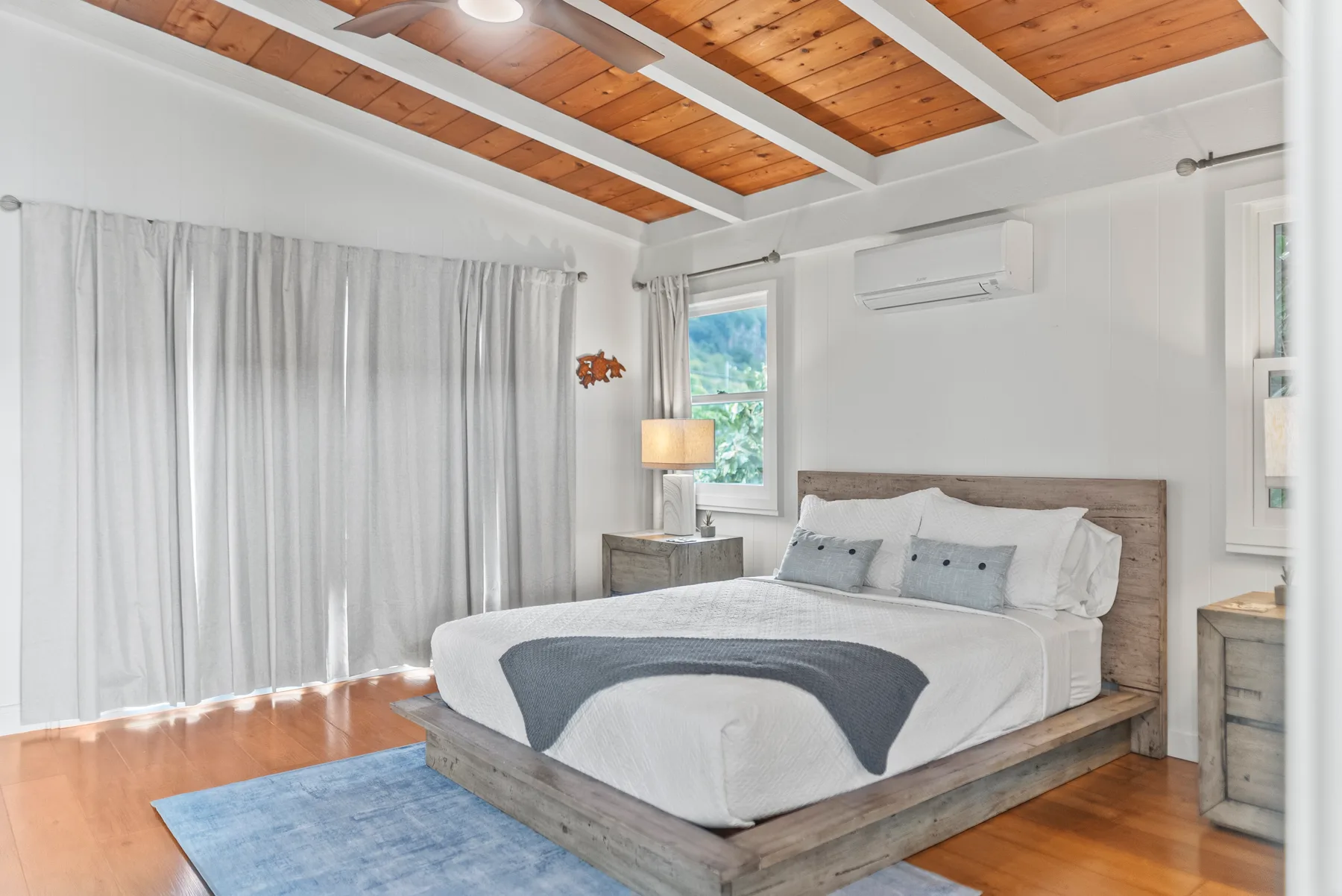 Un dormitorio luminoso con una cama grande bajo un techo revestido de madera.