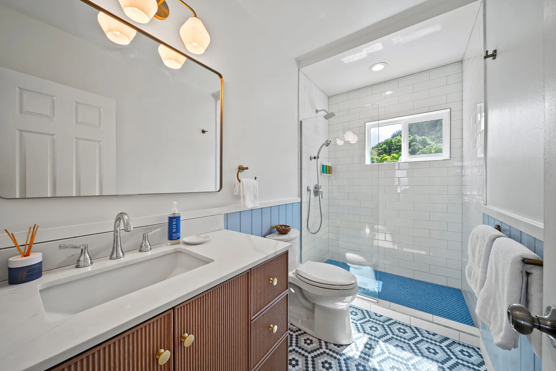 Un baño luminoso con un tocador largo y una ducha alicatada.
