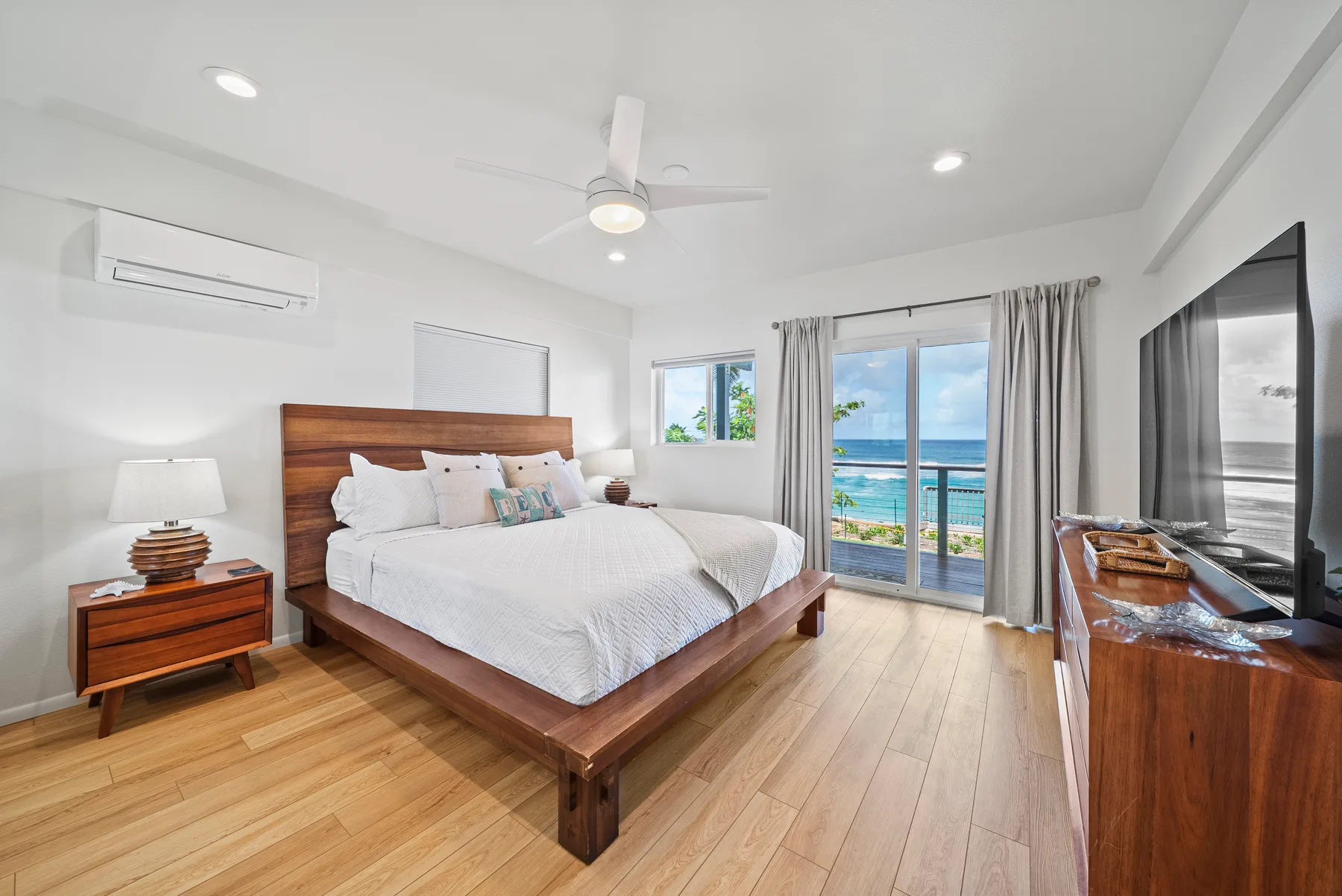 Un dormitorio luminoso con una cama grande y puertas corredizas de vidrio hacia un balcón.