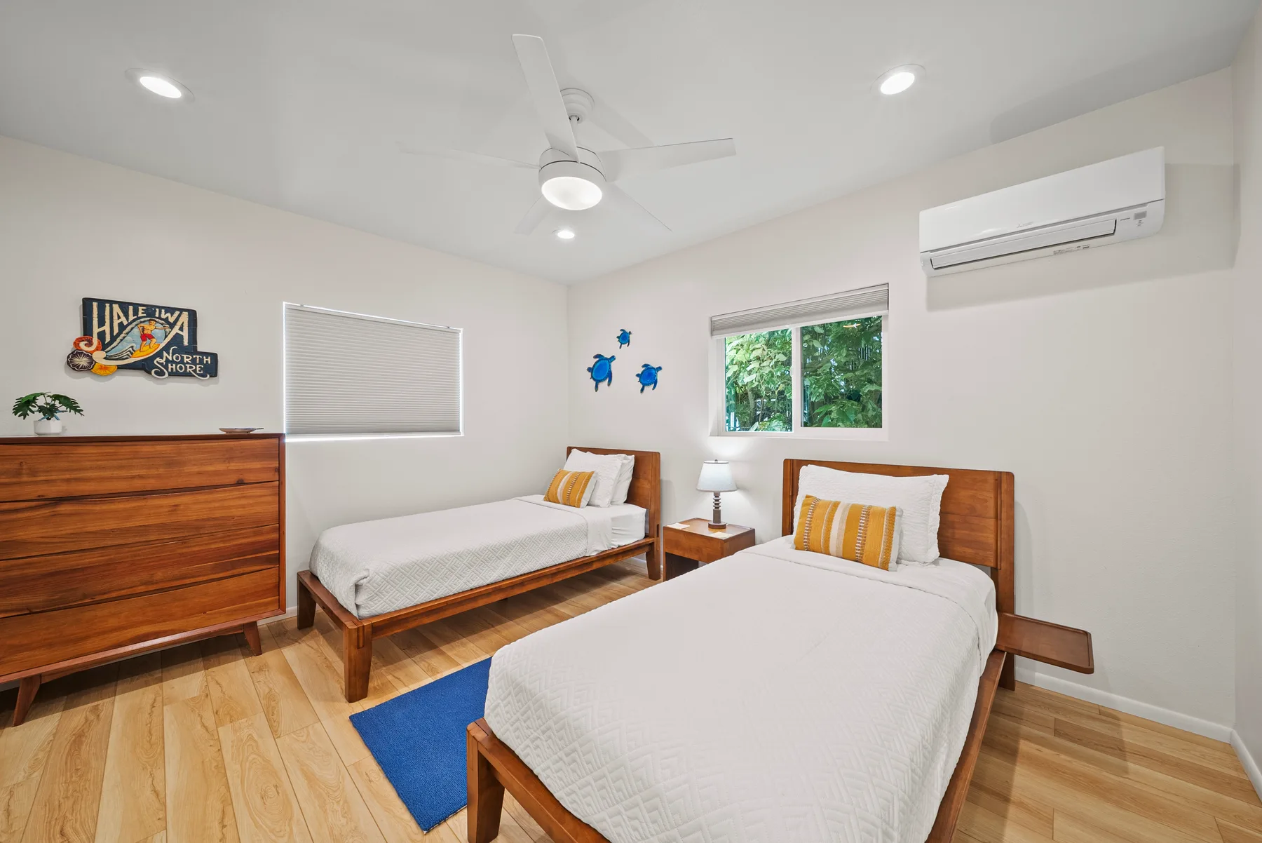 Un dormitorio con dos camas, una cómoda de madera y una ventana.