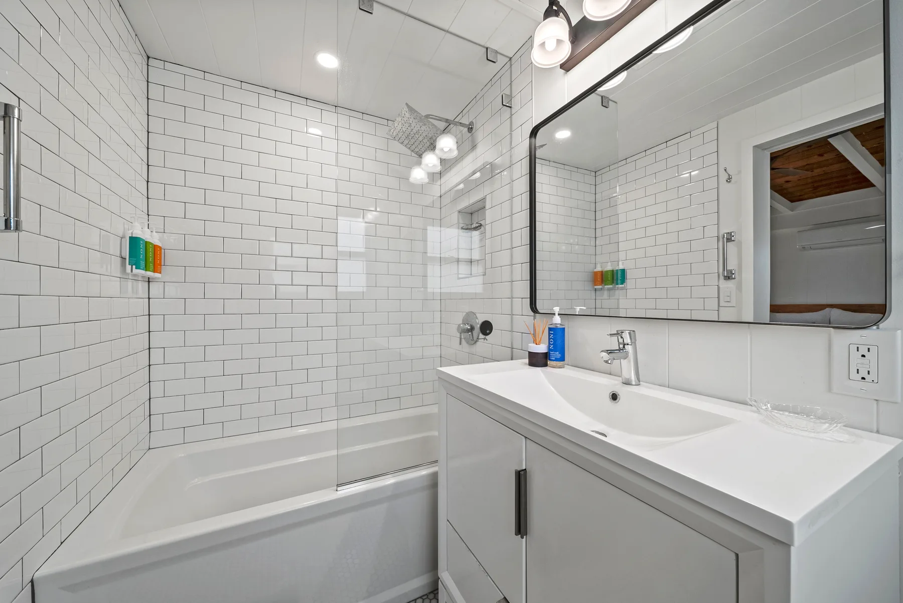 Un baño luminoso con bañera, paredes revestidas de azulejos y un amplio tocador.