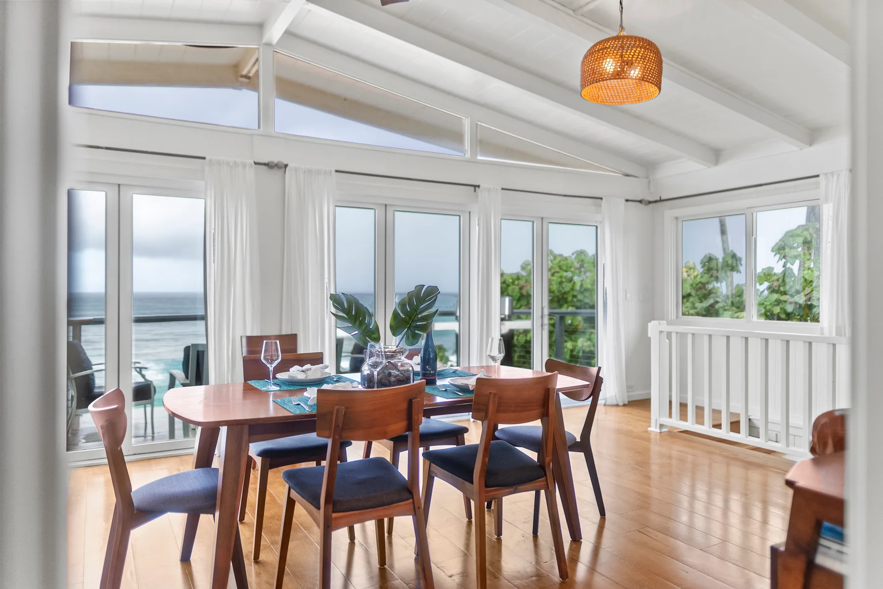 Un comedor luminoso con una mesa de madera junto a grandes ventanas con vista al agua.