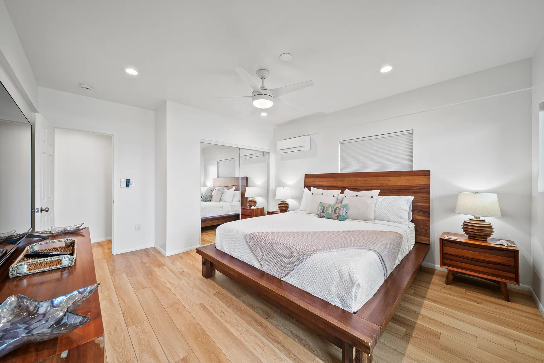 Un dormitorio luminoso con cama de madera, mesitas de noche y suelo de madera clara.