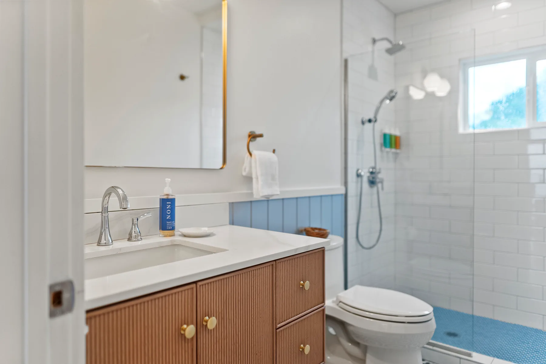 Un baño luminoso con lavabo, inodoro y ducha con mampara de vidrio.