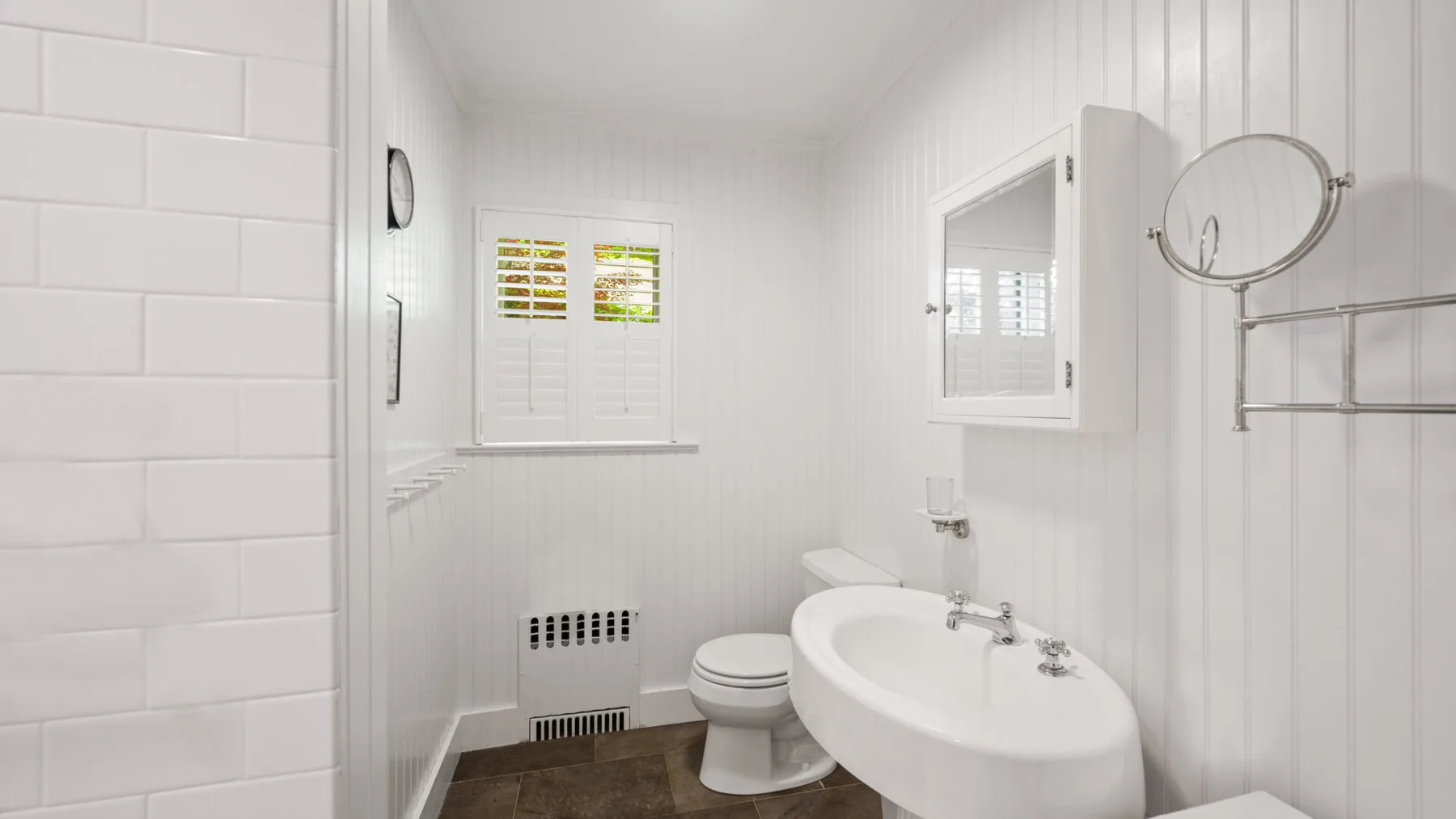 A bright bathroom with a bathtub, toilet, and wall-mounted sink.