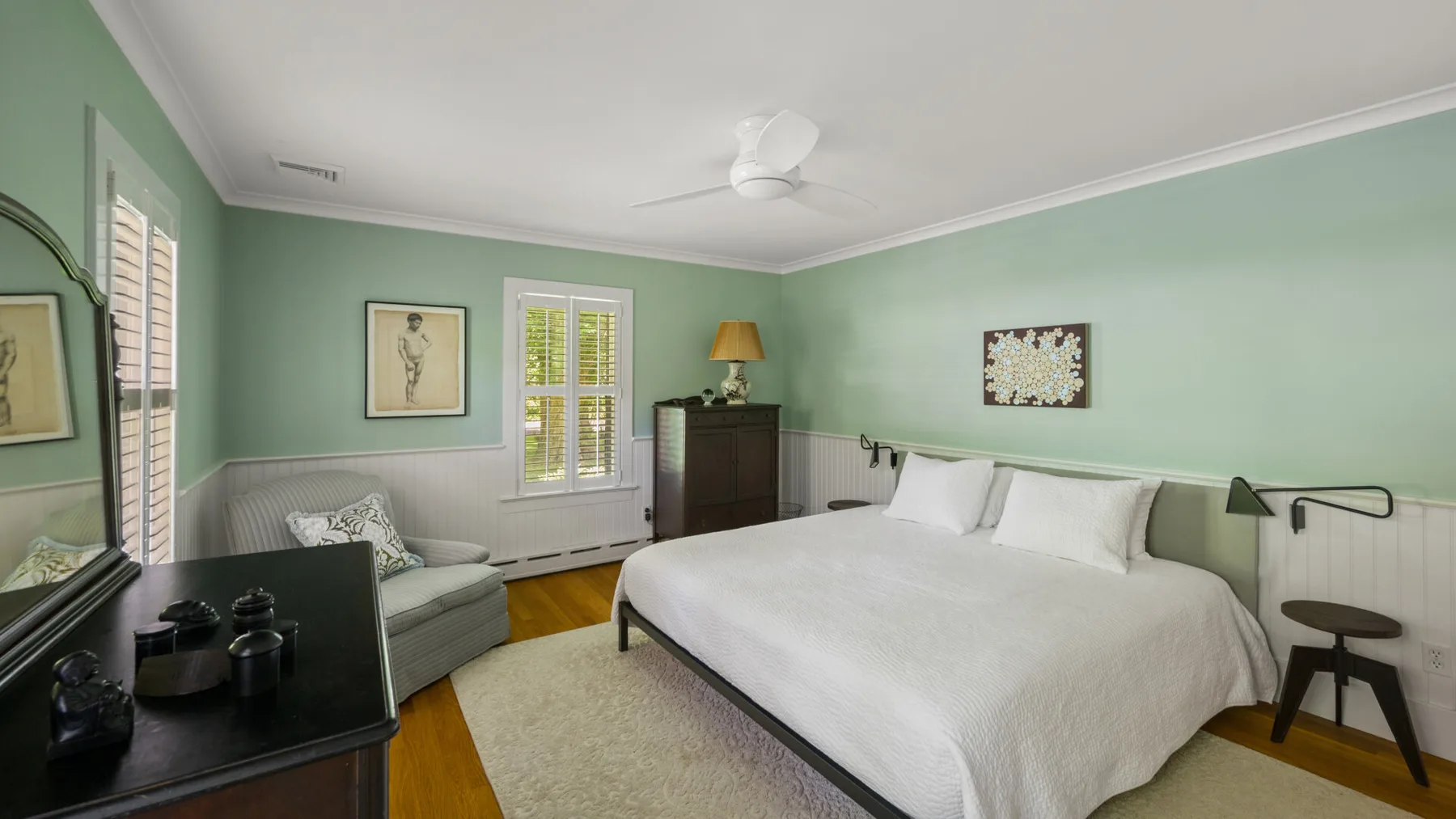 A bedroom with a large bed, a bedside table, and mint-green walls.