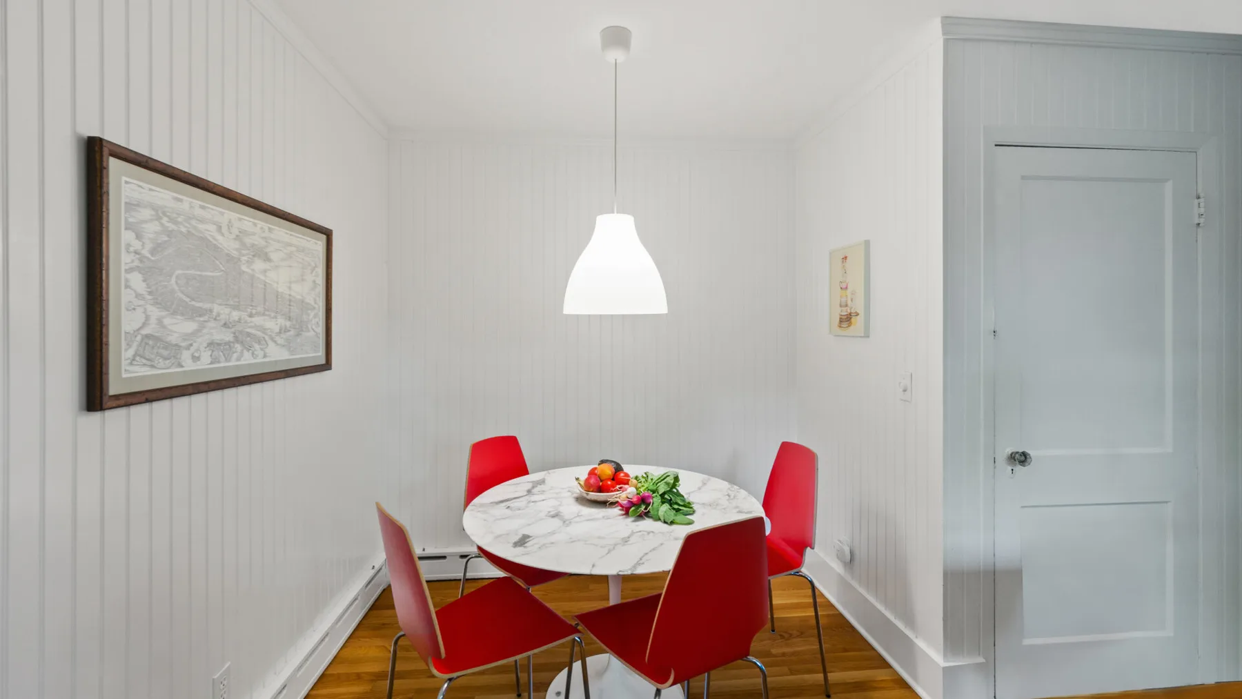 A dining area with a round table, red seating, and a hanging light.