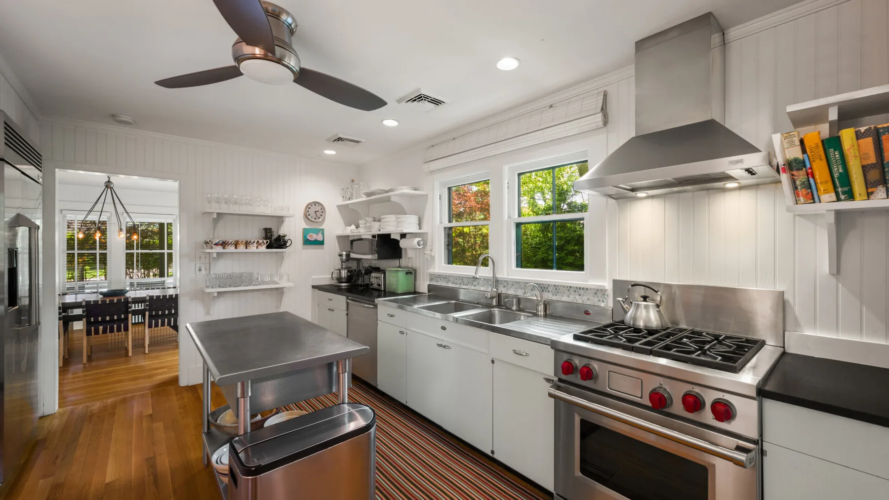 A bright kitchen with a stainless steel range and central worktable.