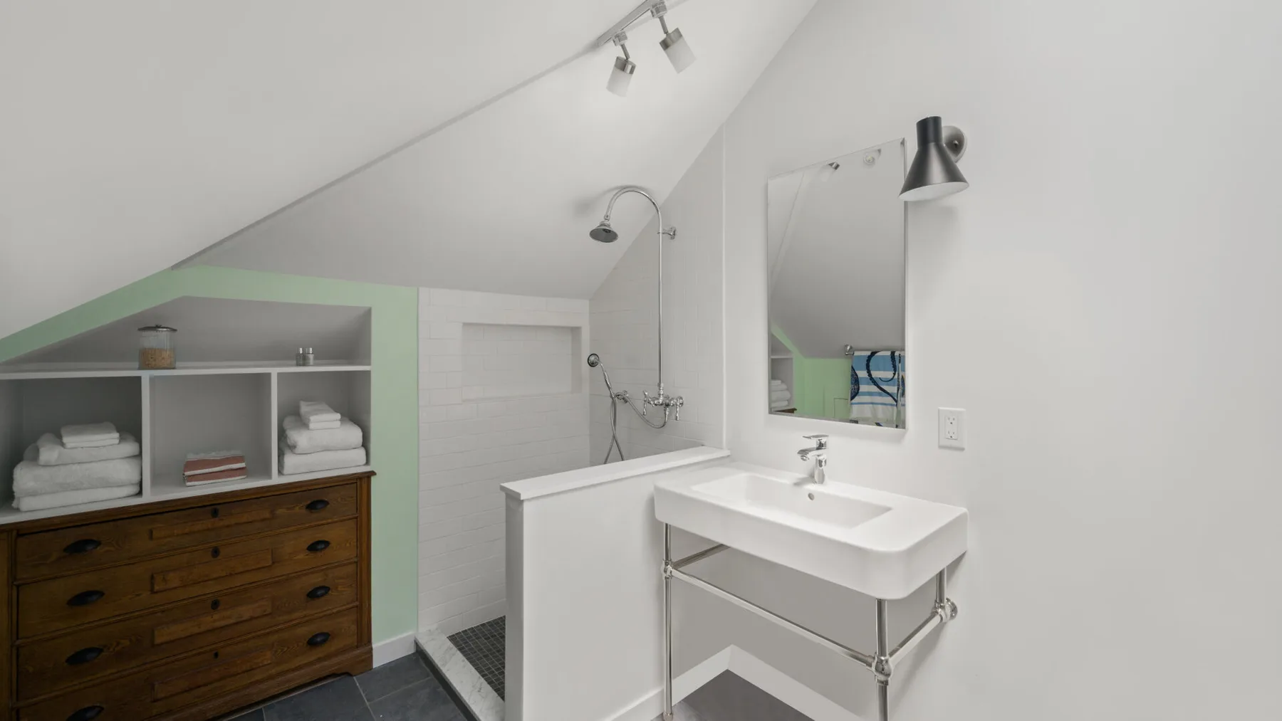 A bathroom with a white sink, mirror, and shower.