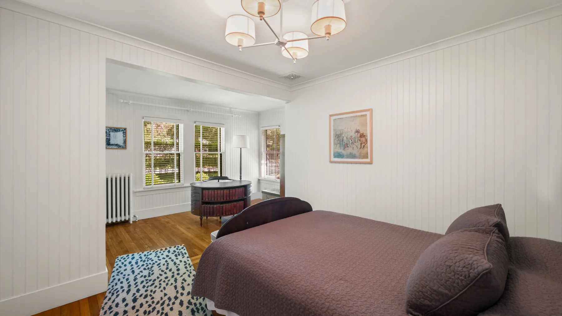 A bedroom with a bed, windows, and a small seating area.