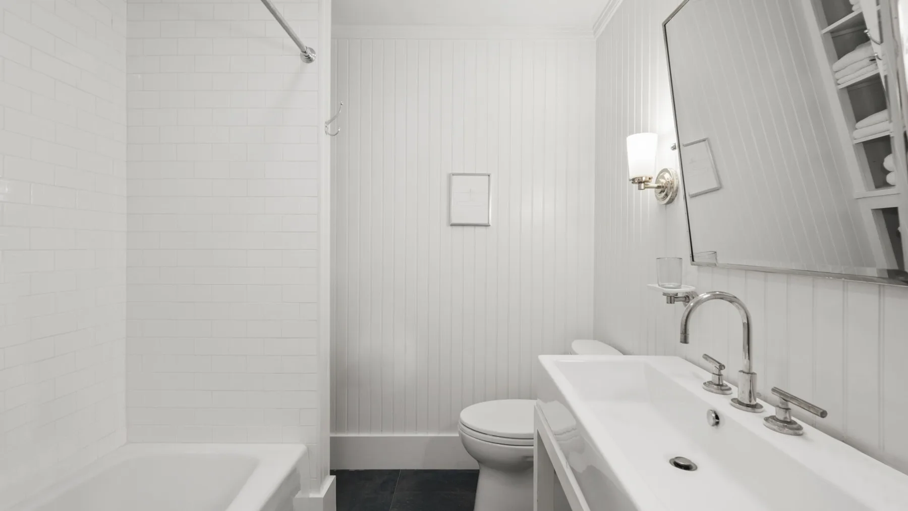 A bright bathroom with a bathtub, toilet, and sink beneath a large mirror.