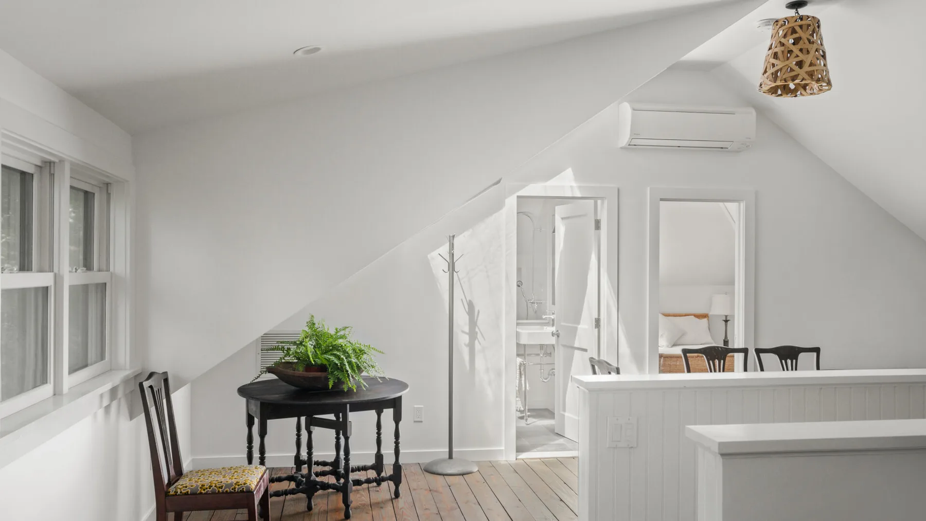 A bright attic room with a small table and windows along the sloped wall.