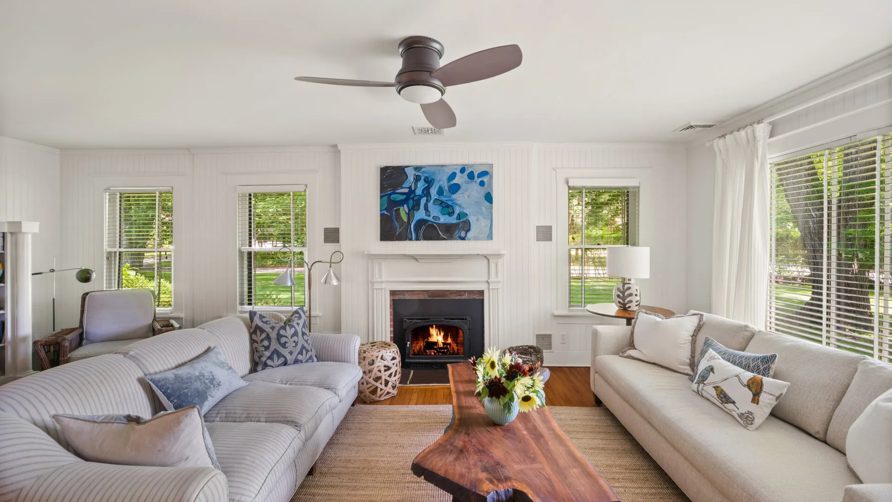 A bright living room with seating arranged around a fireplace and coffee table.