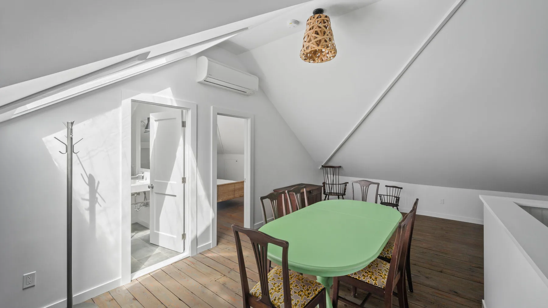 An attic dining area with a green table and wooden seating.