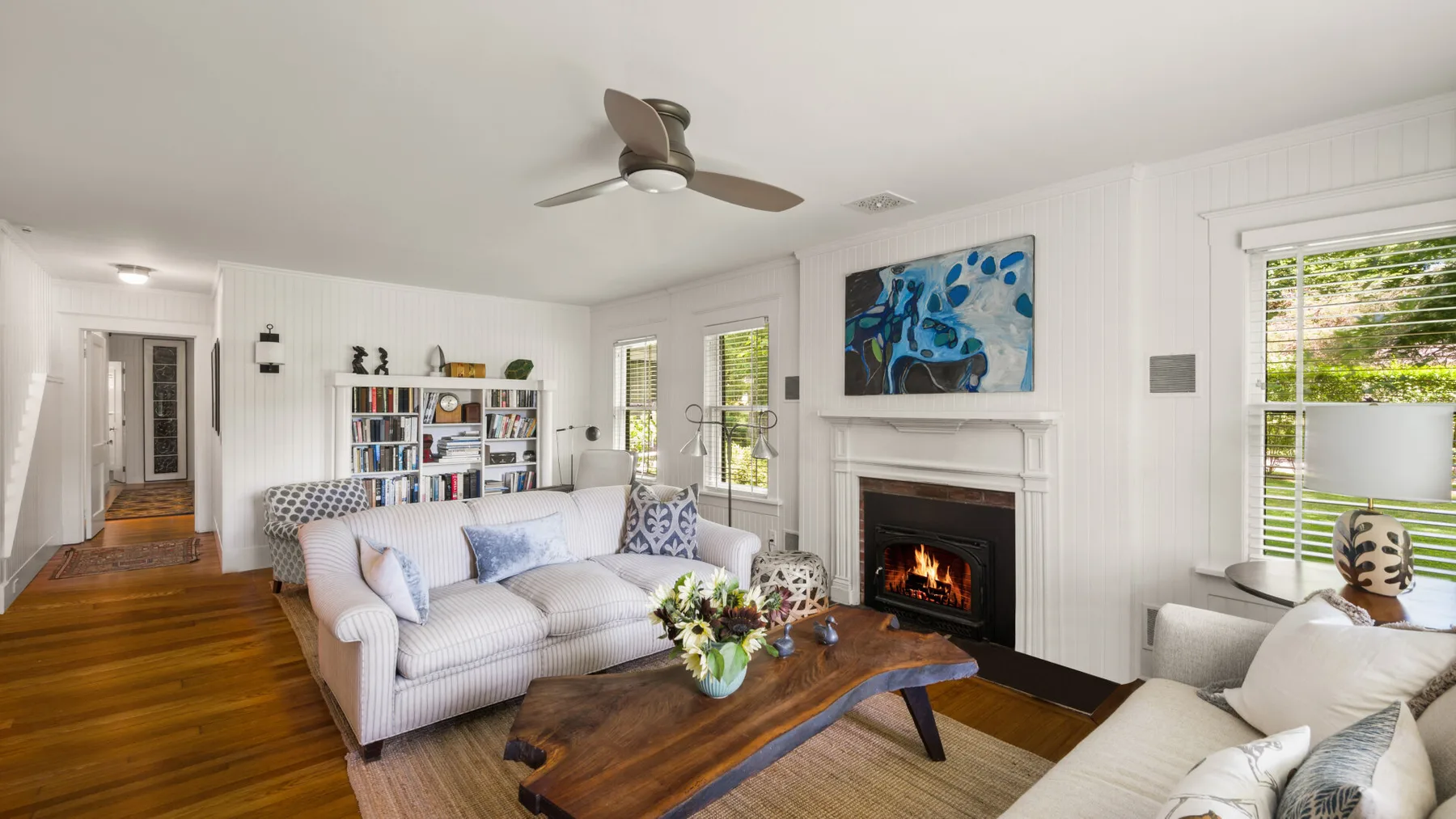 A bright living room with seating, a fireplace, and large windows.