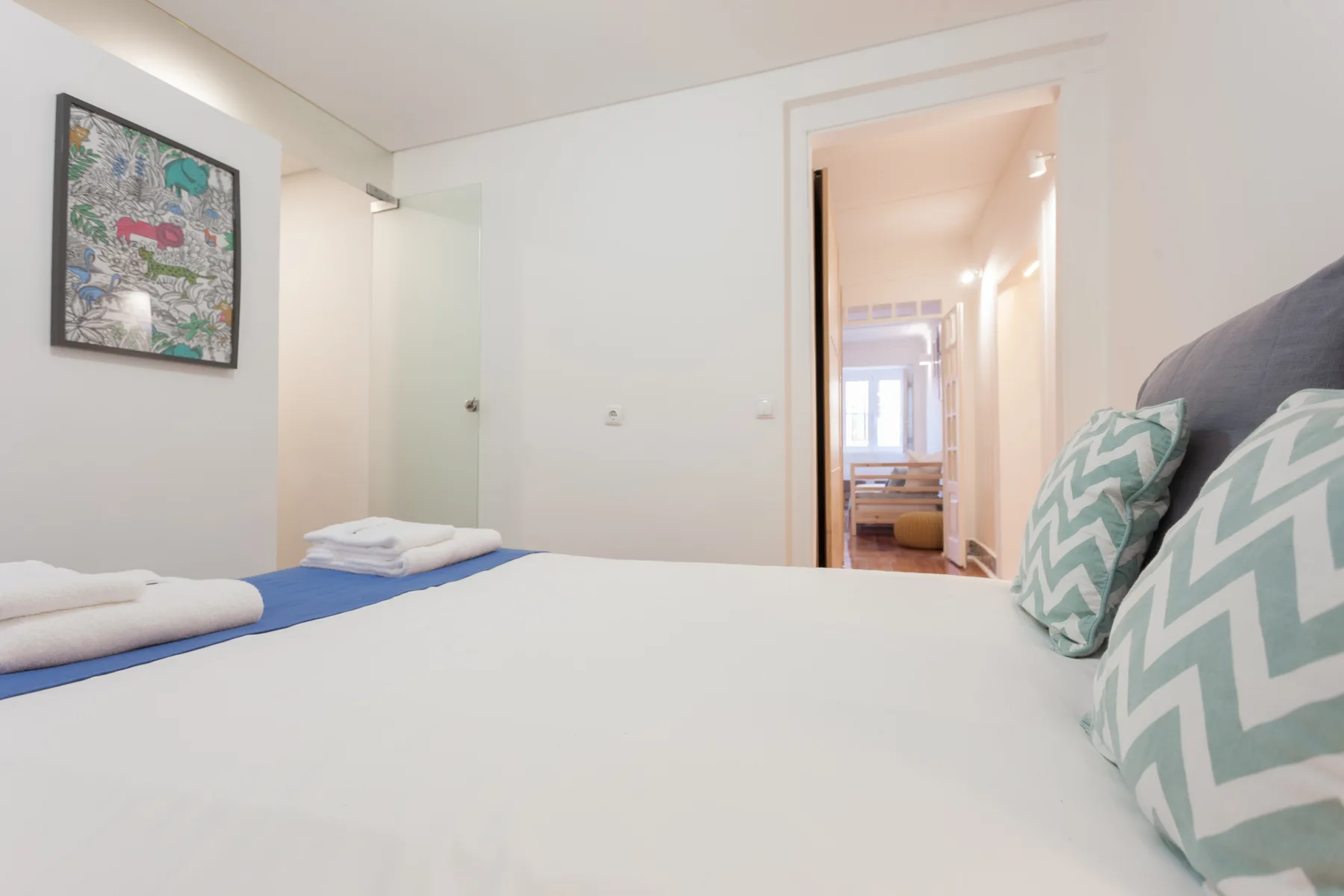 Un dormitorio con una cama bien hecha y una obra enmarcada en la pared.