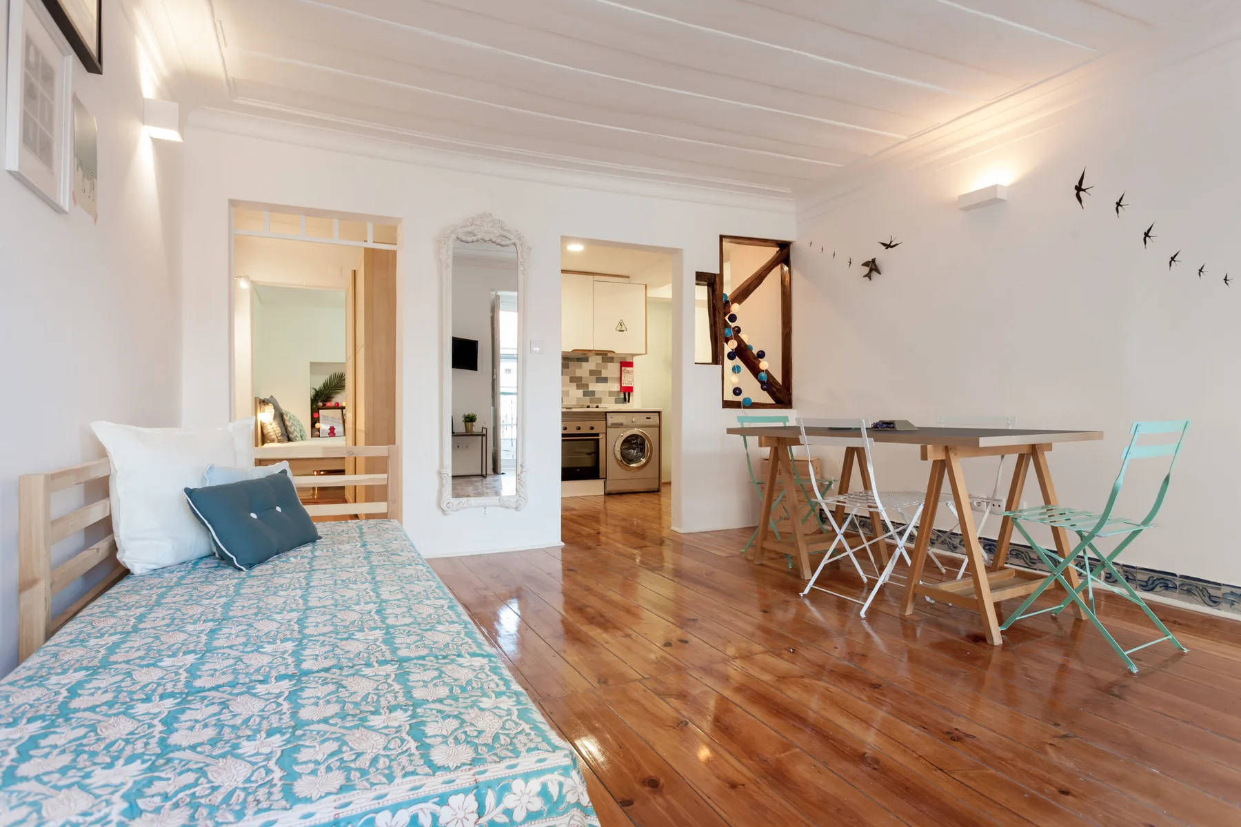 Estudio luminoso con cama, mesa de comedor y cocina compacta.