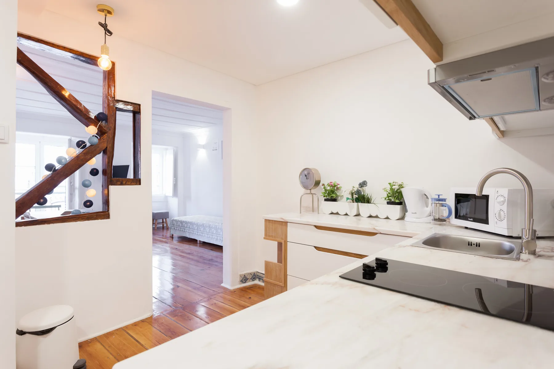 Una cocina luminosa con encimera, placa de cocción, fregadero y microondas.