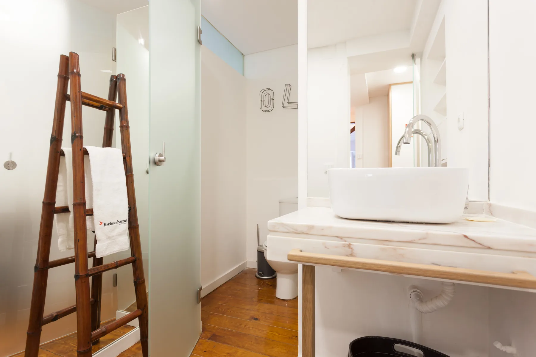Un baño con un lavabo blanco sobre encimera y una escalera de madera para toallas.