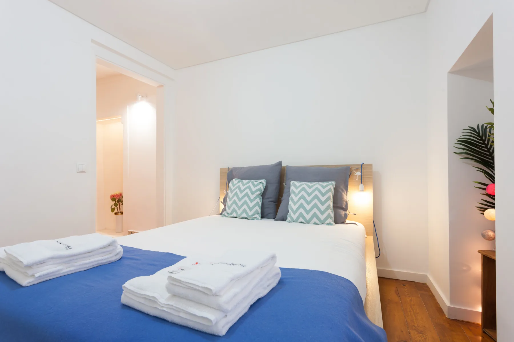Dormitorio con una cama vestida de azul y cojines estampados.