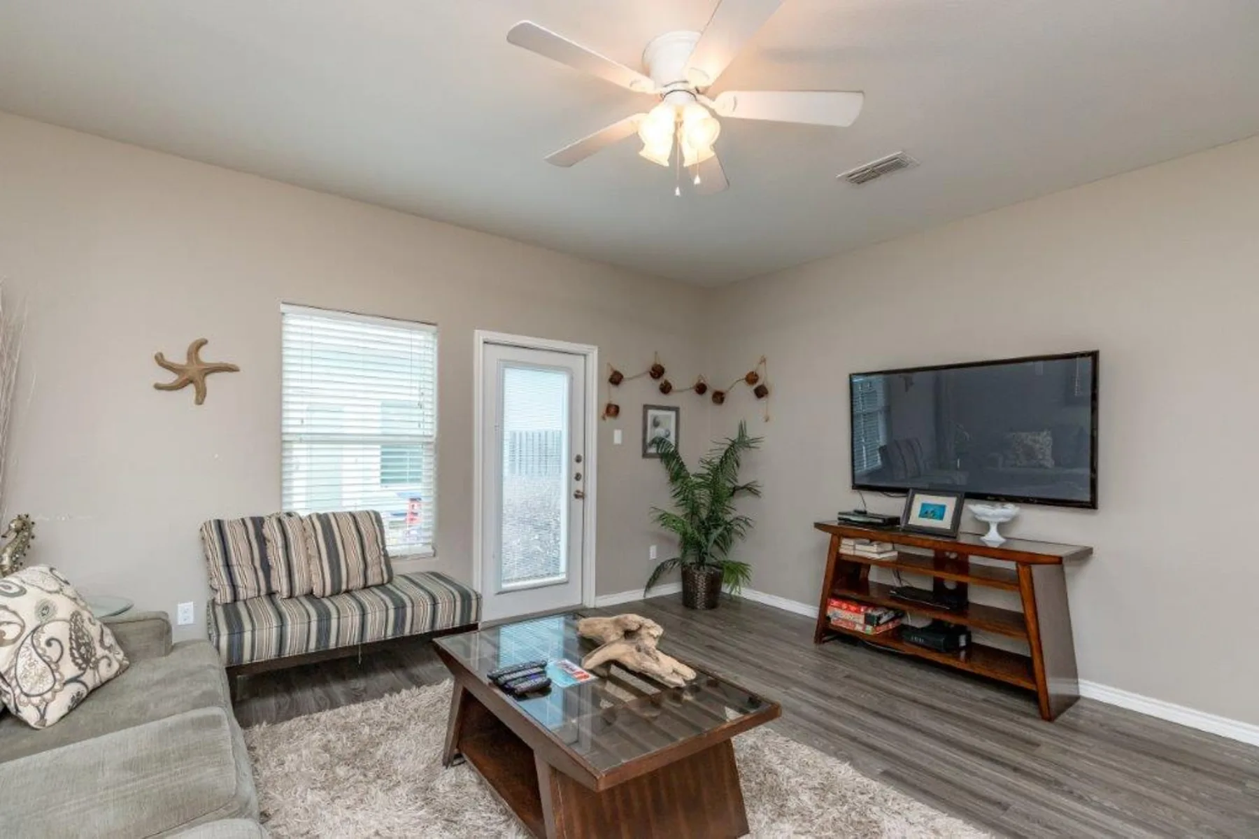 A living room with a television, striped seating, and a glass coffee table.