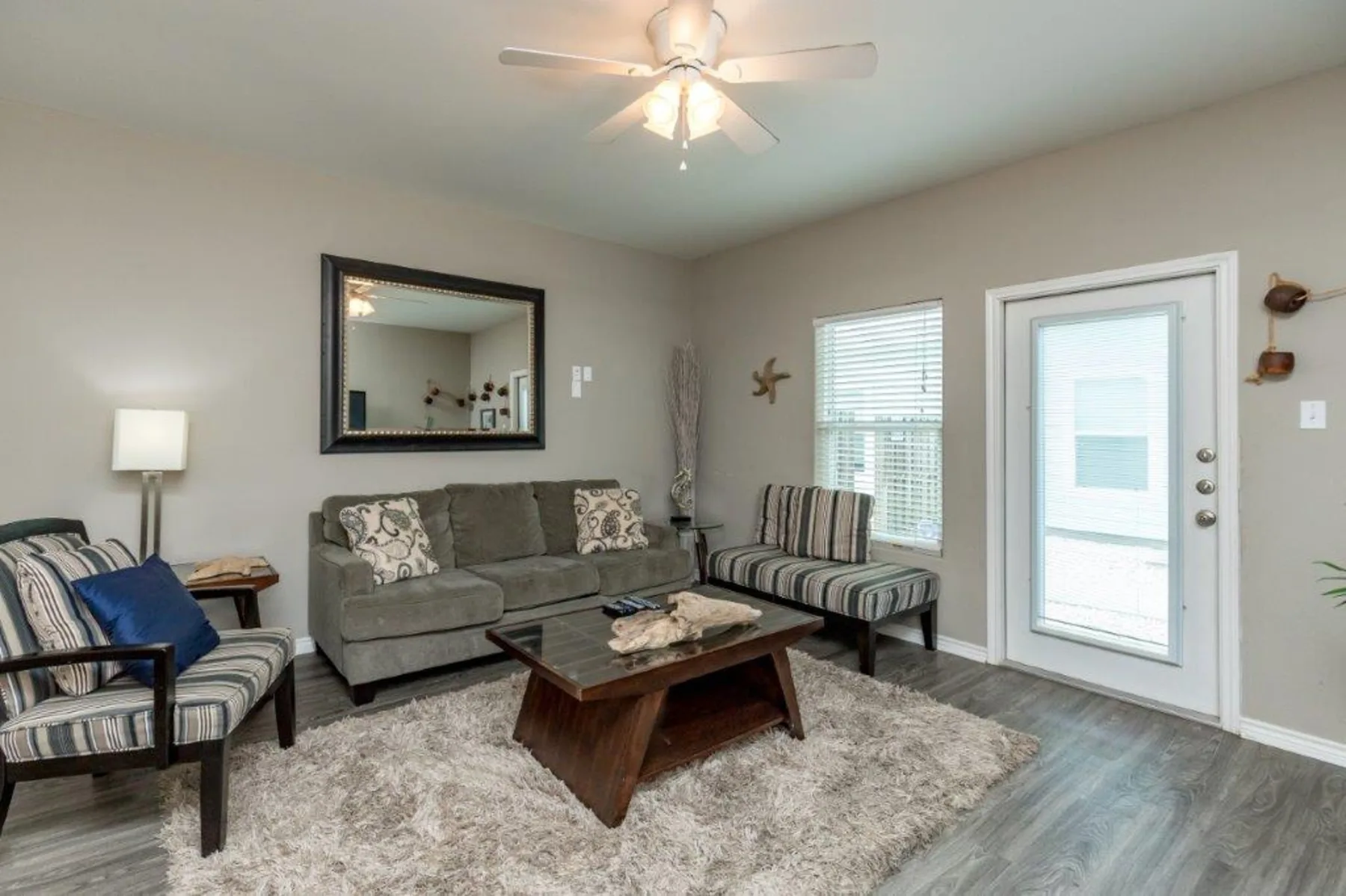 A living room with a gray sofa, striped seating, and a coffee table.
