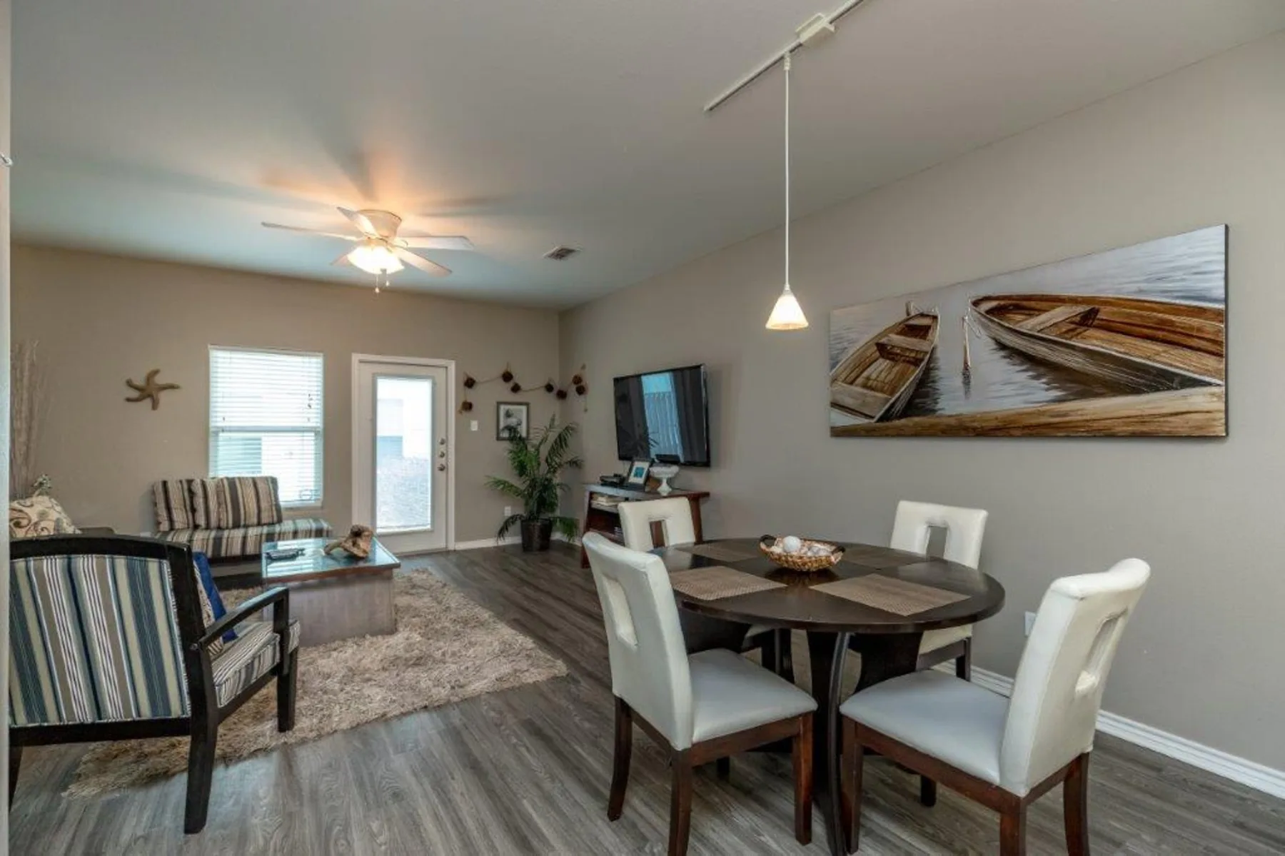 A living and dining area with seating, a dining table, and wall art.