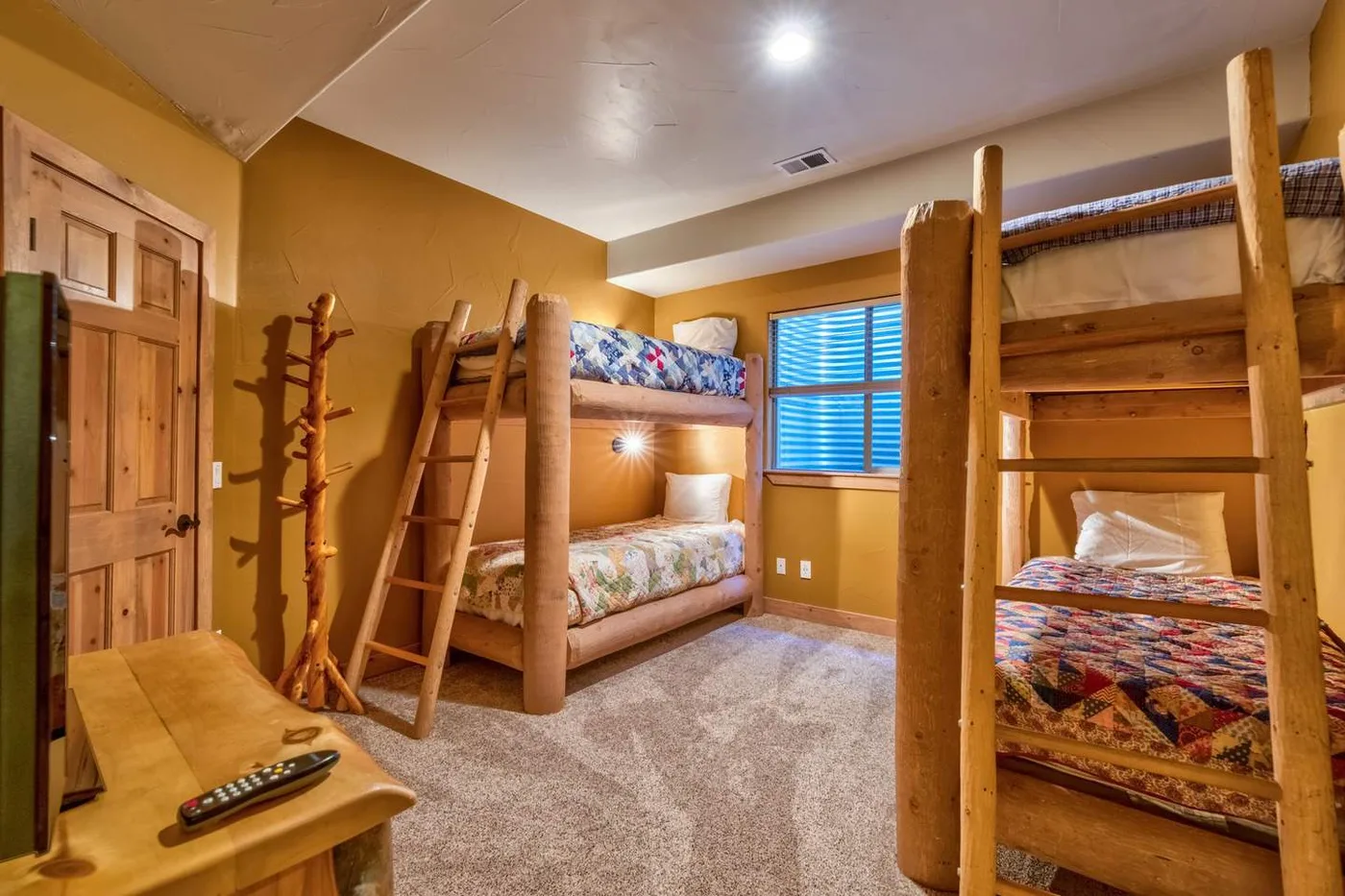Un dormitorio con literas de madera, ropa de cama colorida y una ventana.