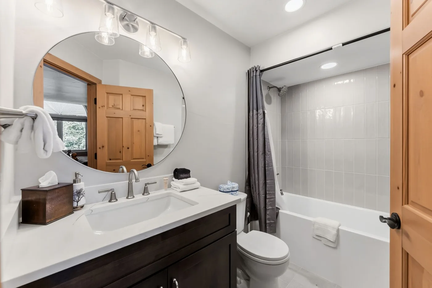 Un baño con lavabo, espejo grande, inodoro y bañera con cortina de ducha.