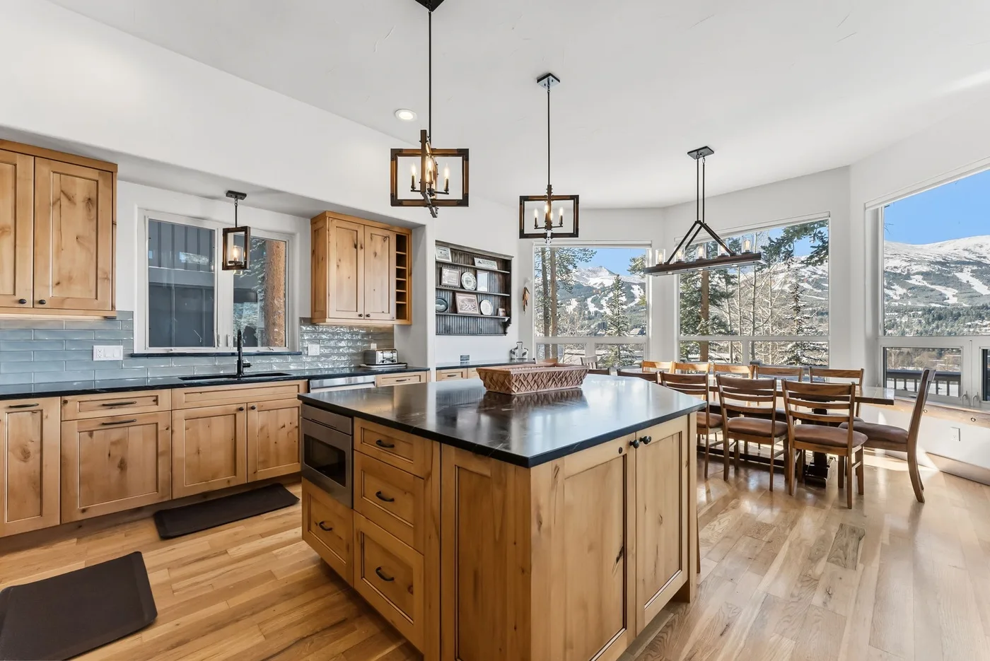 Una luminosa cocina y comedor con una isla central y grandes ventanas.