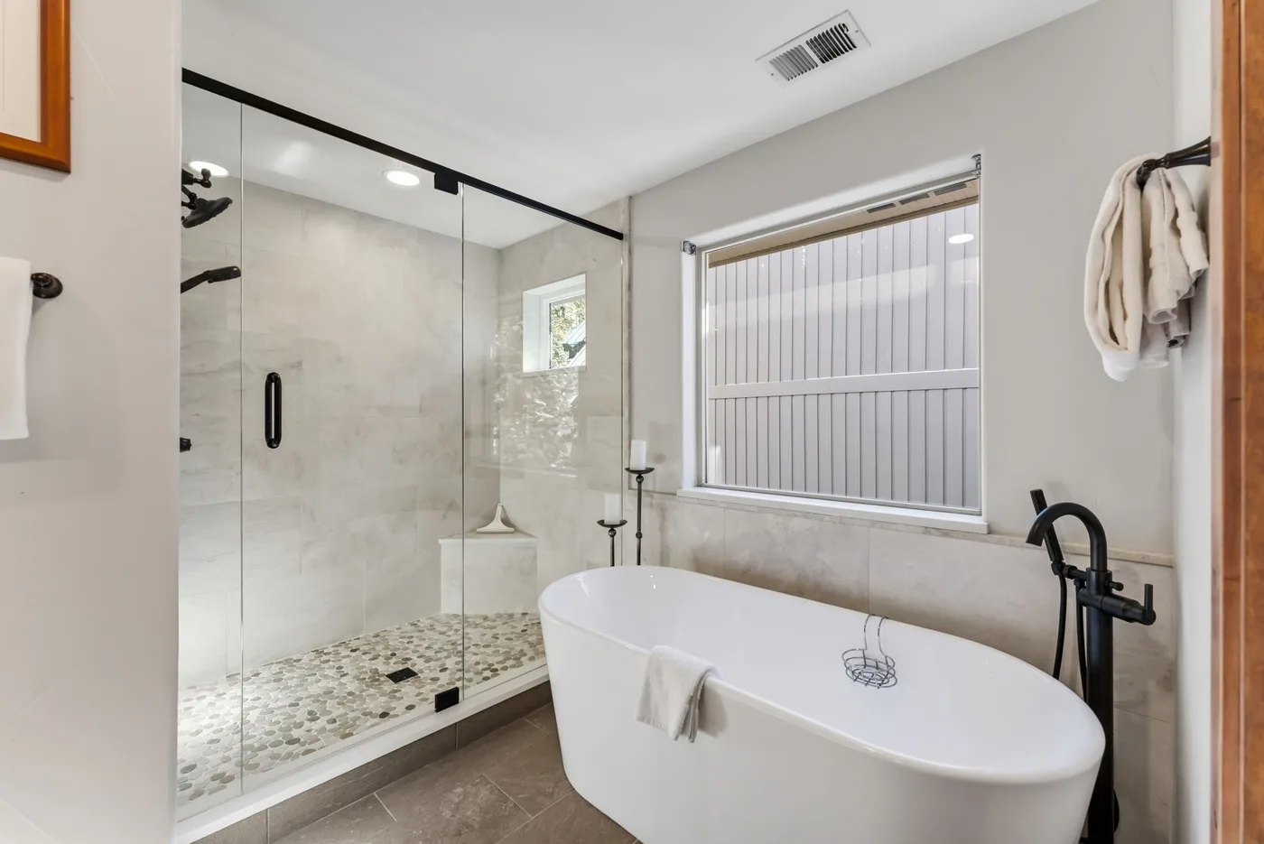 Un baño con bañera independiente y ducha con mampara de vidrio.