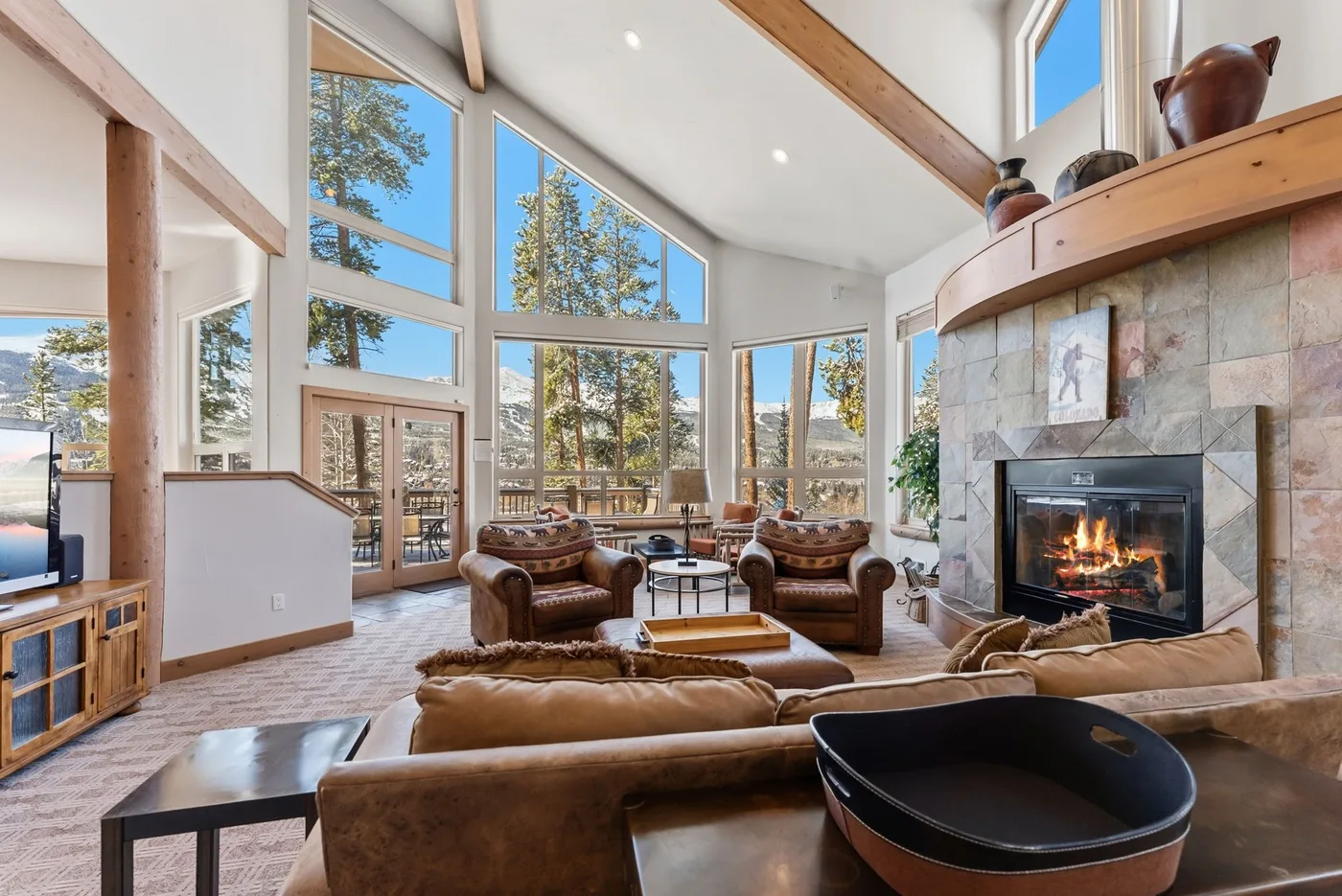 Una sala luminosa con grandes ventanales, asientos y una chimenea de piedra.
